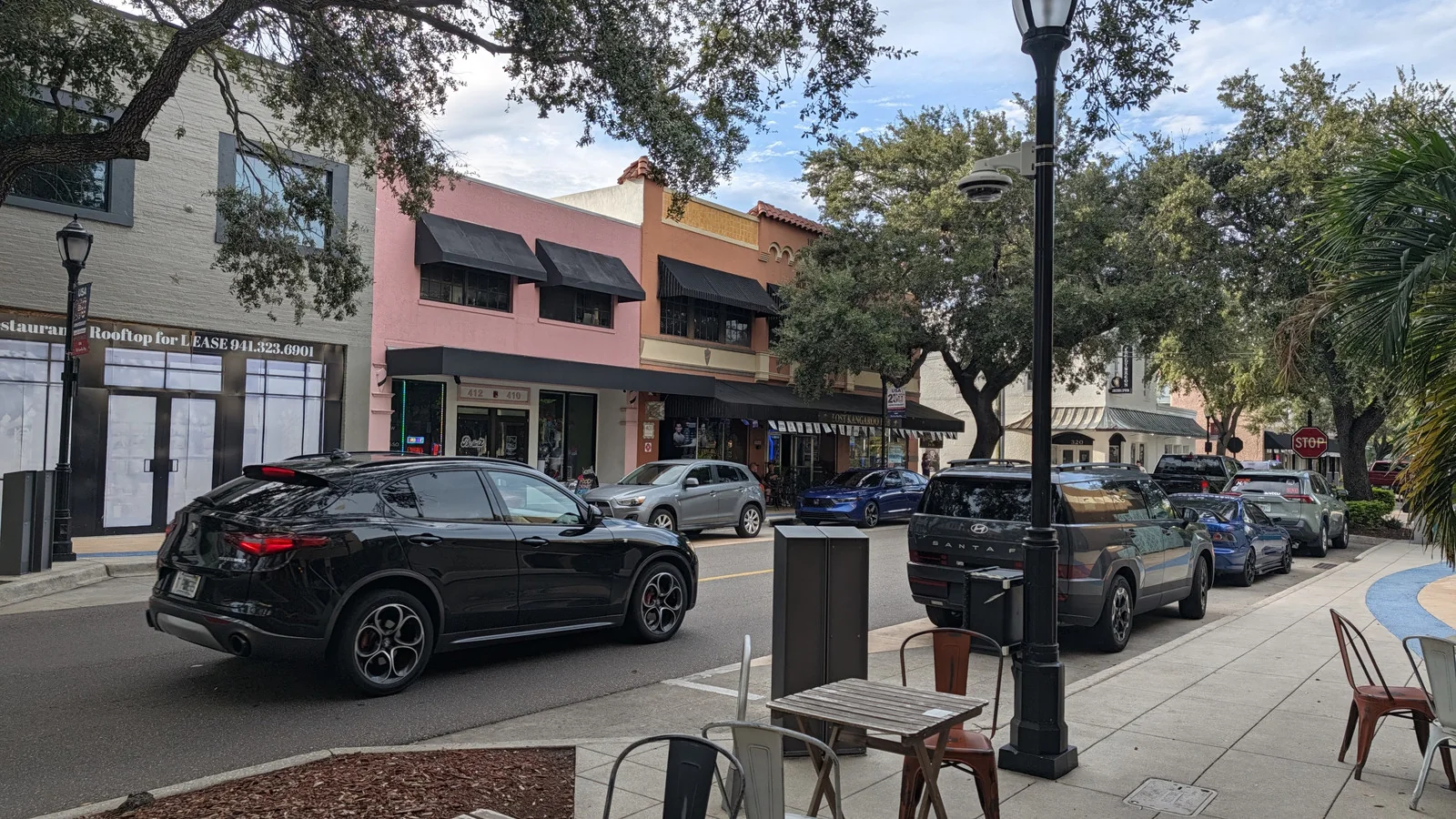 Old Main Street in Downtown Bradenton, Florida: historische Ladenzeile mit Markisen, Cafétischen und alten Eichen